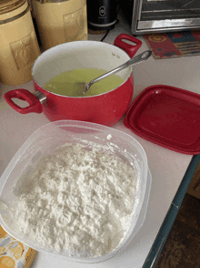 a container of white powder next to a red pot