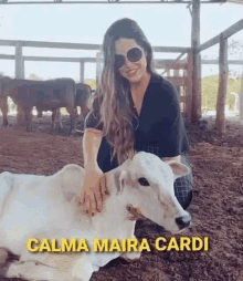 a woman is kneeling down next to a white cow in a pen .