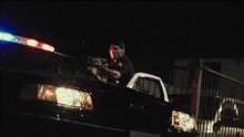 a police officer is standing in the back of a police car at night