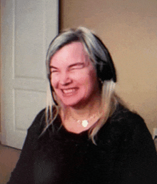 a woman wearing a headset and a necklace smiles