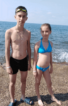 a boy and a girl are posing for a picture on a beach