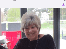 a woman is smiling in front of a window with a rooster on it that says cockmoor