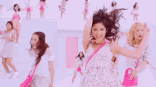 a group of young women are dancing together in a pink room .