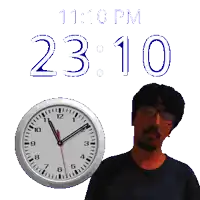a man is standing next to a clock that says 23:10
