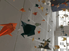 a bunch of origami birds hanging from a ceiling