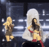 two women are dancing on a stage in front of a giant screen .