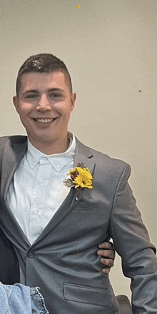 a man in a suit with a yellow flower in his pocket smiles