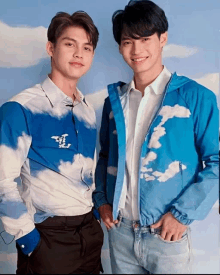 two young men are posing for a picture and one of them is wearing a blue jacket with clouds on it