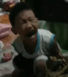 a baby is crying with his mouth open while sitting on the floor .