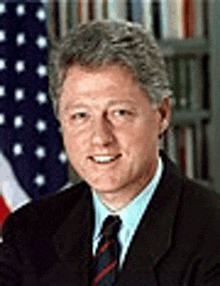 a man in a suit and tie is standing in front of a flag .