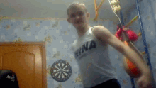 a man in a tank top is dancing in front of a dartboard .