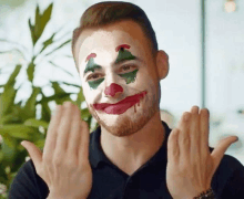 a man with a clown face painted on his face is making a funny face