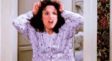 a woman in a pajama top is holding her hair in her hands and screaming .