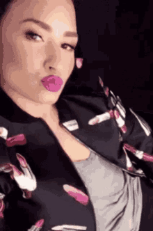 a woman is wearing a jacket with lipsticks on it and making a funny face .