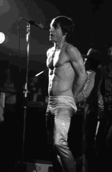 a shirtless man is singing into a microphone on a stage