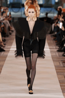 a model walks down the runway at a fashion show wearing a black outfit