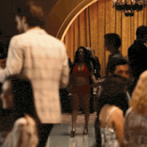 a woman in a red bikini is walking through a crowded room