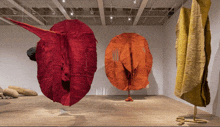 a row of red and yellow sculptures hanging in a room