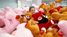 a woman is laying in a pile of stuffed animals including a teddy bear that says i love you on its face