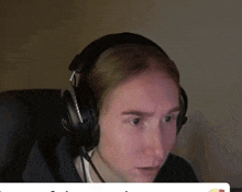 a man wearing headphones with a microphone looks at the camera