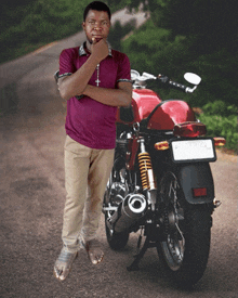 a man in a purple shirt stands next to a red motorcycle on a road