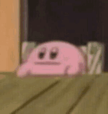 a pink cartoon character is peeking out from behind a table .