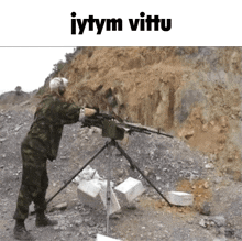 a man in a military uniform is holding a gun on a tripod in front of a rocky hillside .