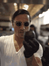 a man wearing sunglasses and a white t-shirt is holding something in his hands .