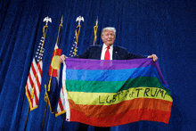 donald trump holds up a rainbow flag with lgbt for trump written on it