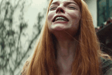 a woman with red hair is smiling and looking up