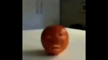 a tomato with a face carved into it is sitting on top of a table .