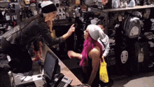 a woman with pink hair is talking to another woman in a store with a backpack that says elf on it