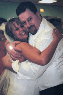 a man in a white shirt is hugging a smiling woman