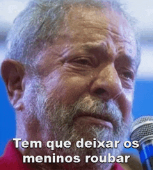 a man with a beard is crying in front of a microphone and the caption says tem que deixar os