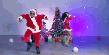 a man and a woman dressed as santa claus dancing in front of a christmas tree