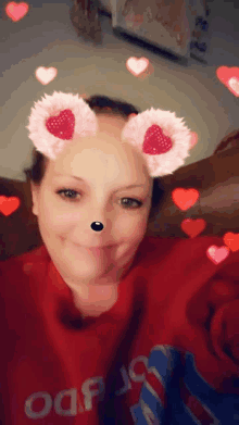 a woman wearing a red sweater and hearts on her face .