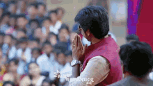 a man in a red vest is praying in front of a crowd and the word romantics is on the bottom