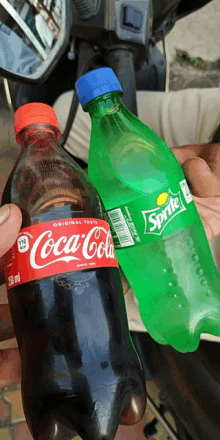 a bottle of coca cola and a bottle of sprite are held together