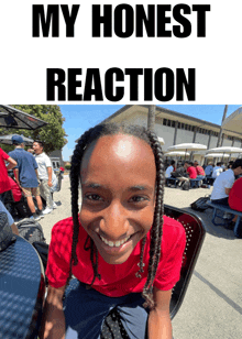 a boy in a red shirt is smiling in front of a sign that says ' my honest reaction '