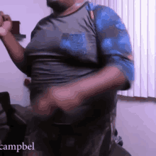 a man in a blue shirt is dancing in front of a window with campbel written on it