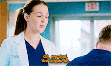 a woman in a lab coat is talking to a man in a blue scrub .