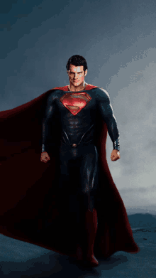 a man in a superman costume stands in front of a cloudy sky