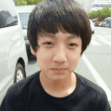 a young boy wearing a black shirt is standing in front of a white van .