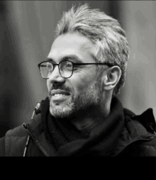 a man wearing glasses and a scarf is smiling