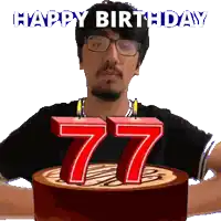 a man with glasses is holding a cake with candles in the shape of the number 77