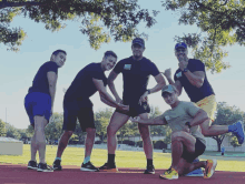 a group of men are posing for a picture and one of them is wearing a shirt that says " athletics "