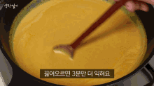 a person stirring a sauce with a wooden spoon