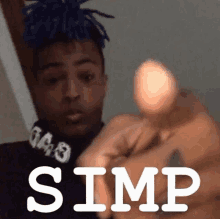 a man with blue dreadlocks is pointing at the camera with the word simp on the bottom