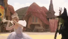 a woman in a white dress is holding a wand in front of a witch in a witch hat .