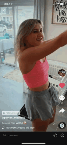 a woman in a pink crop top and grey shorts is standing in front of a crib